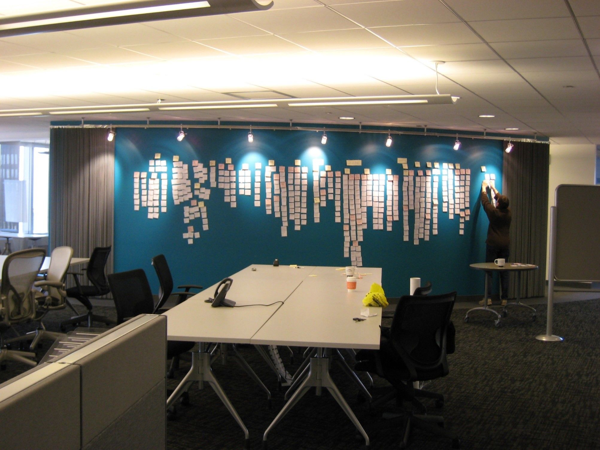 Photo of a wall across a room of a large affinity diagram taking up most of the wall using post-its.
