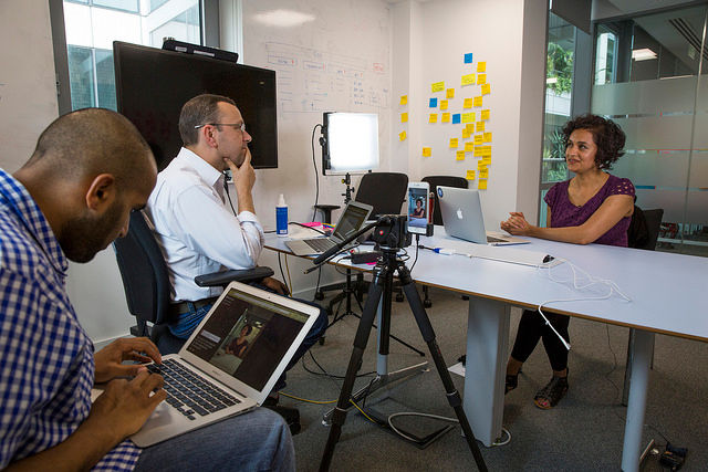 Interviewing session with notetaker in the background and video camera set up.