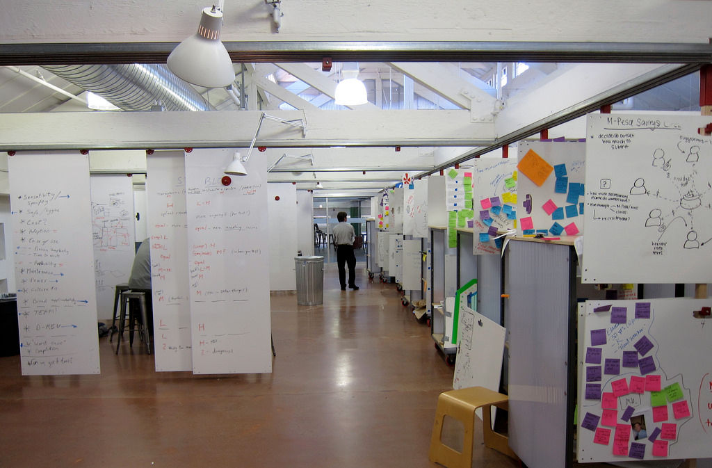 Photo of a studio at Stanford's design school showing sliding whiteboards with lots of post its and notes on the whiteboards.