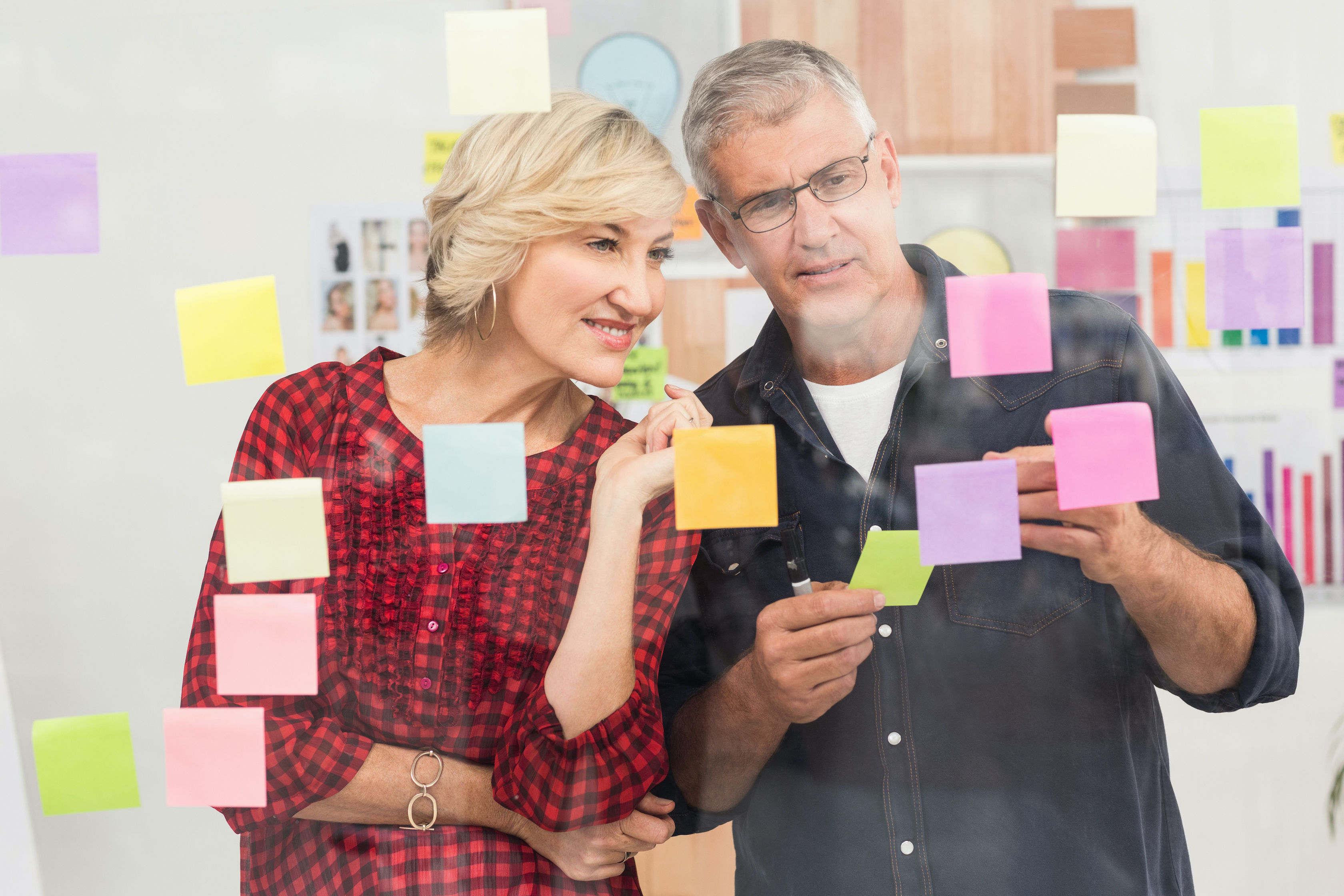 Photo of people arranging post its on a glass wall.